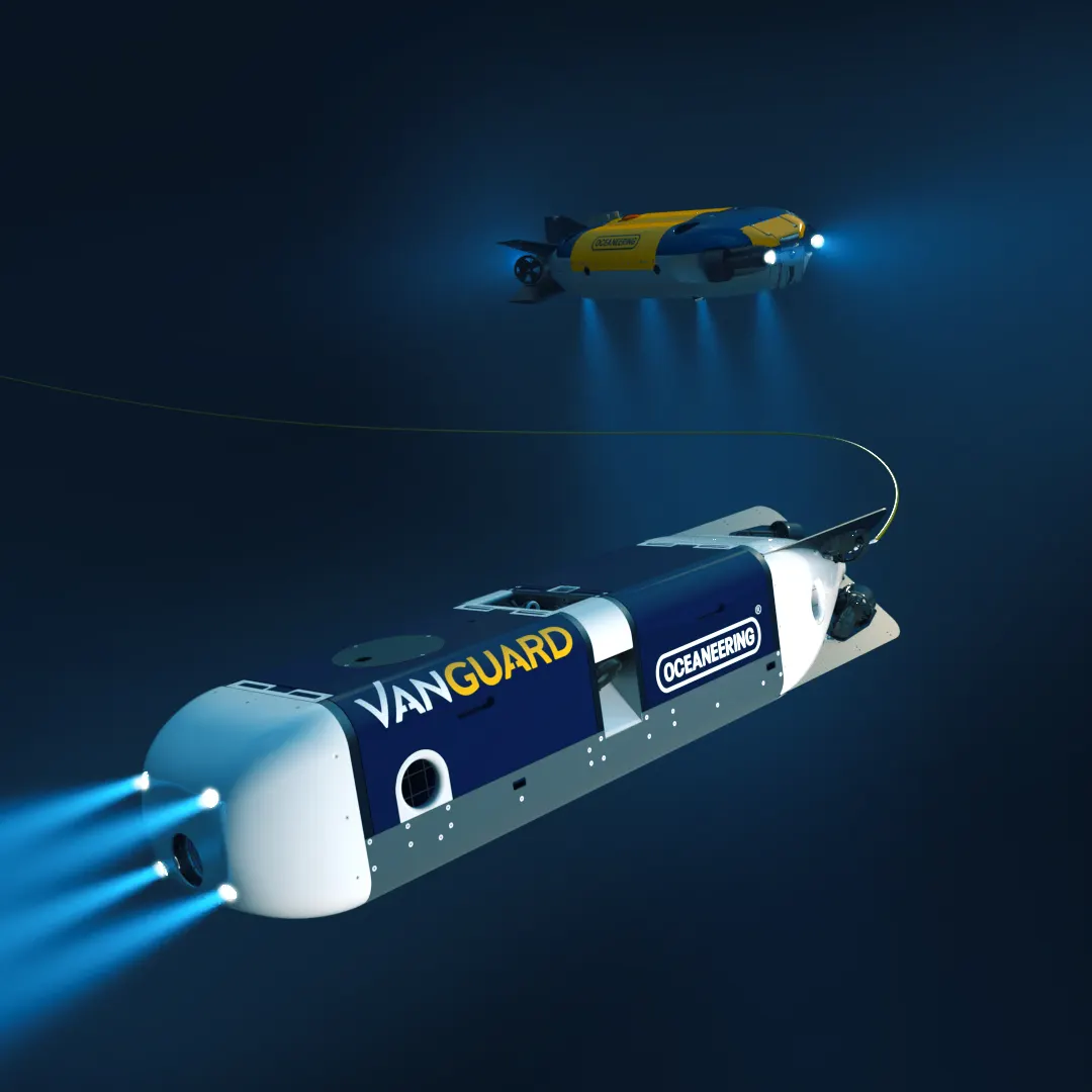 Oceaneering subsea vehicles underwater, a large Vanguard vehicle running lights with a smaller tethered ROV above it